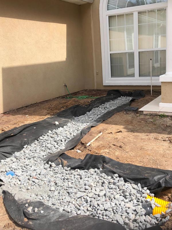 Clean stone backfill over filter fabric next to a foundation