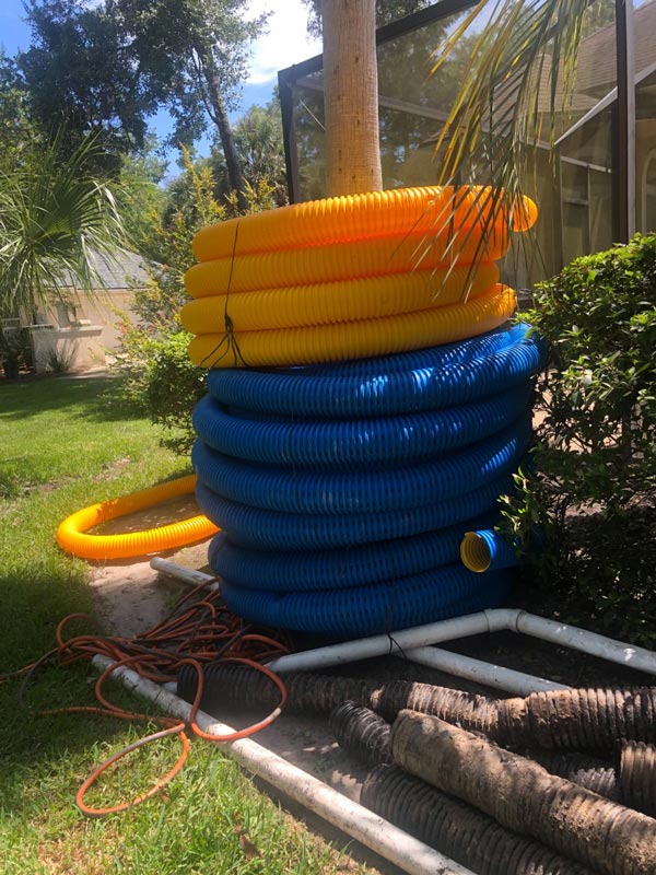 Rolls of blue and yellow corrugated drainage pipe on site
