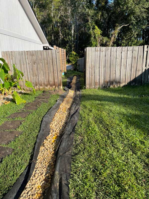 River rock filled French drain running along a fence line